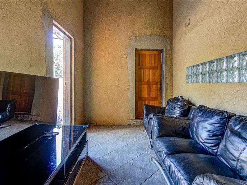 Living room featuring tiled flooring, high ceilings, and a decorative glass block wall, requiring finishing touches to the plasterwork around the door frames.