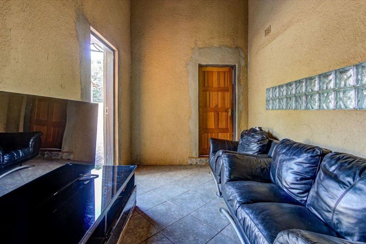 Living room featuring tiled flooring, high ceilings, and a decorative glass block wall, requiring finishing touches to the plasterwork around the door frames.