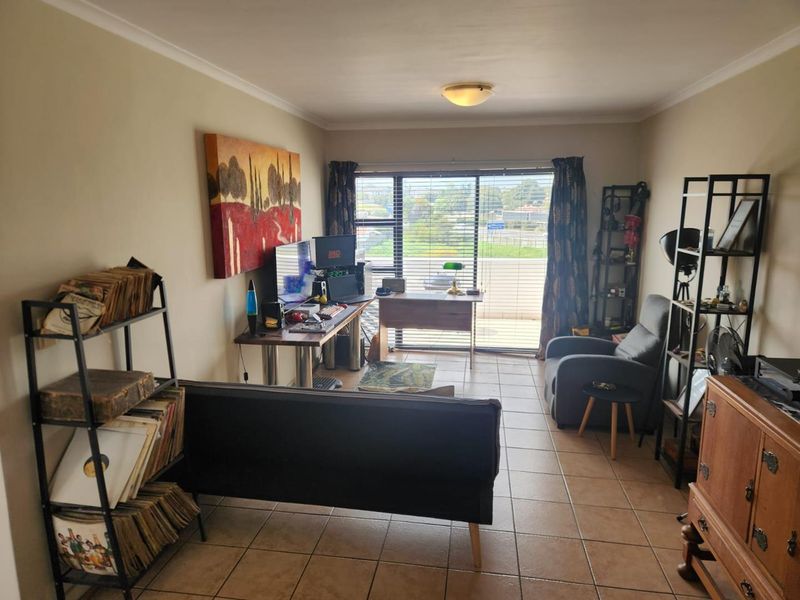 A living room featuring tiled flooring and a large sliding glass door that provides natural light and access to an outdoor area.