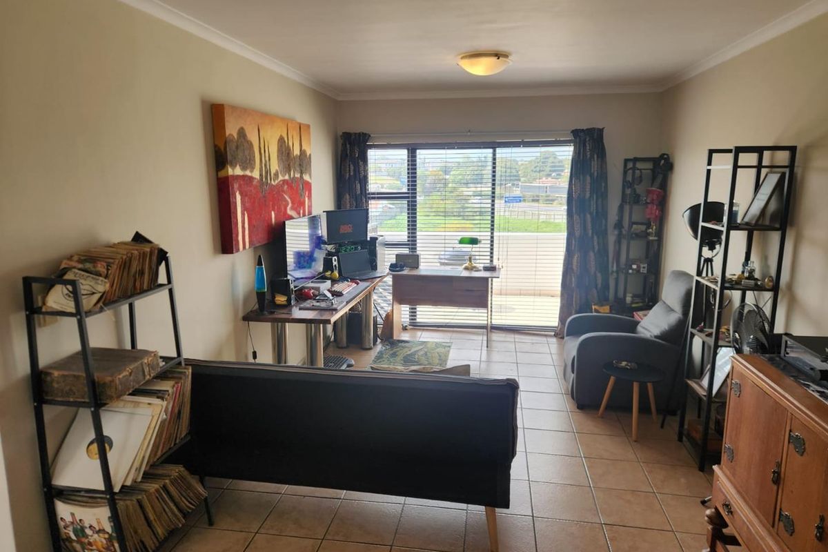 A living room featuring tiled flooring and a large sliding glass door that provides natural light and access to an outdoor area.