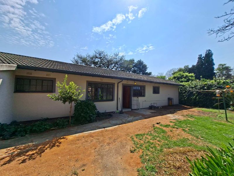 Rear view of the house featuring a tiled roof, steel-framed windows, and a stone paved walkway leading to the entrance.