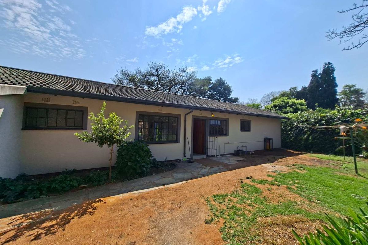 Rear view of the house featuring a tiled roof, steel-framed windows, and a stone paved walkway leading to the entrance.