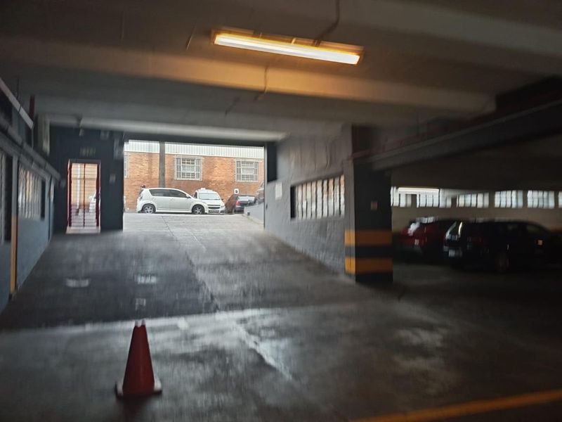 A functional underground parking garage area featuring a concrete ramp, overhead lighting, and painted structural columns.