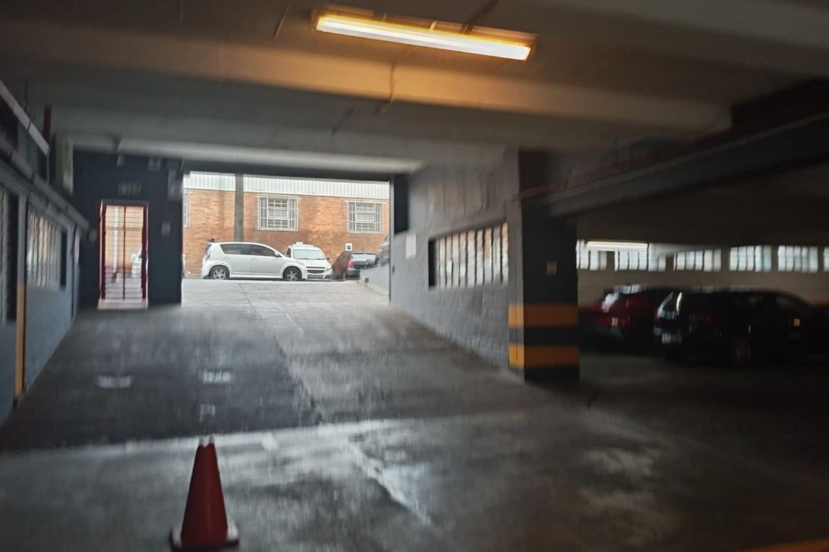 A functional underground parking garage area featuring a concrete ramp, overhead lighting, and painted structural columns.