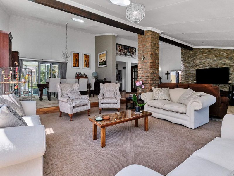 Spacious open-plan living and dining area featuring exposed timber beams, a rustic brick column, stone-clad feature wall, and natural light from skylights.
