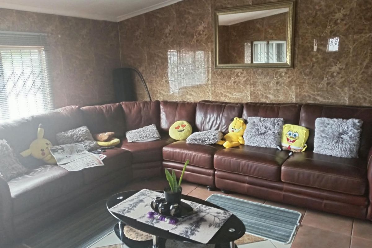 Living room featuring marble-effect wall tiling and tiled flooring, providing a dated aesthetic that could be updated with modern finishes.