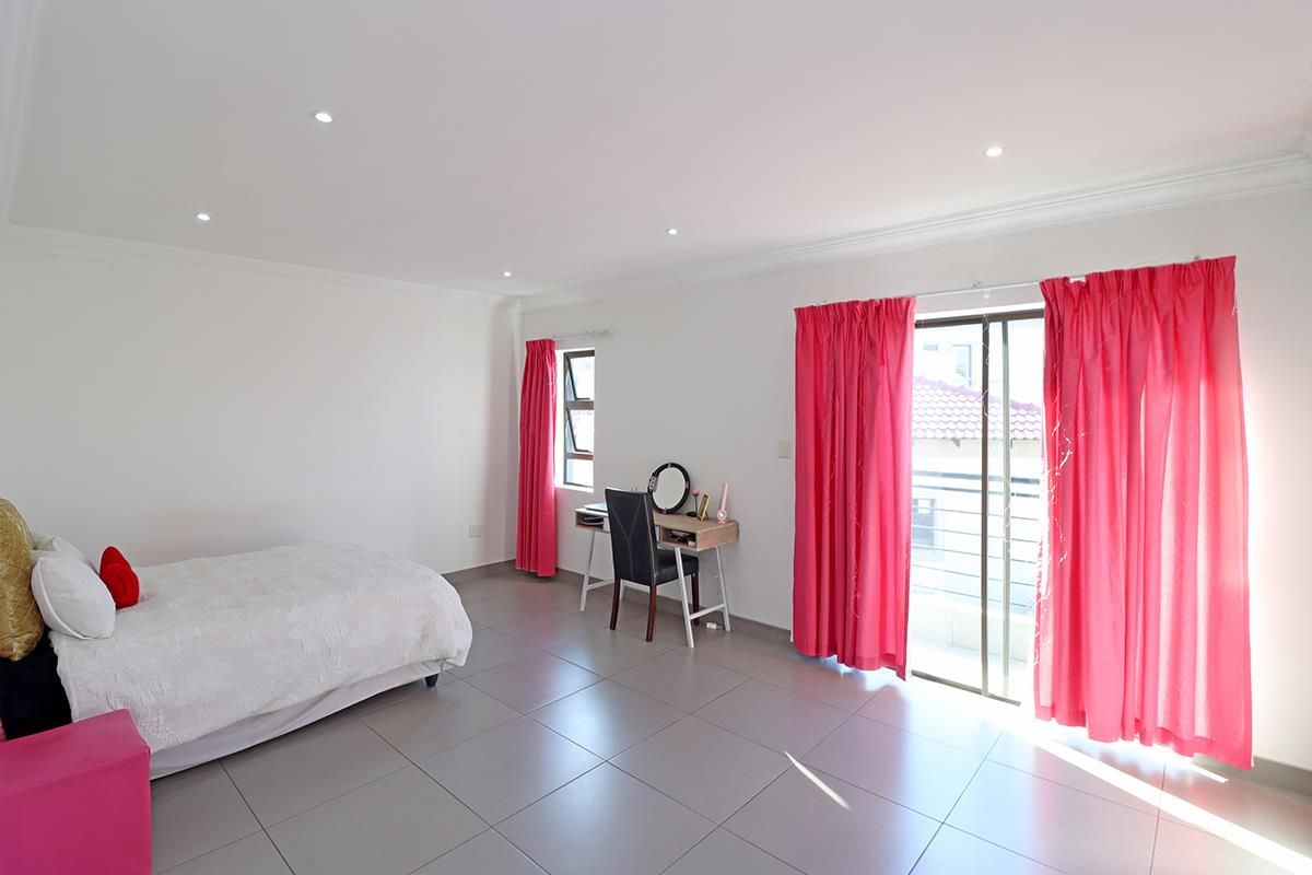 Spacious bedroom featuring neutral tiled flooring, recessed downlighting, and direct access to a private balcony through sliding glass doors.