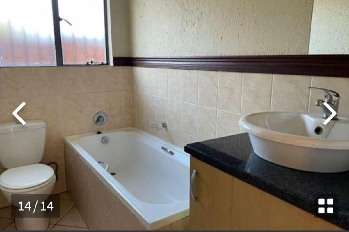A functional bathroom featuring a built-in bathtub, a vanity with a countertop basin, and tiled wall accents.