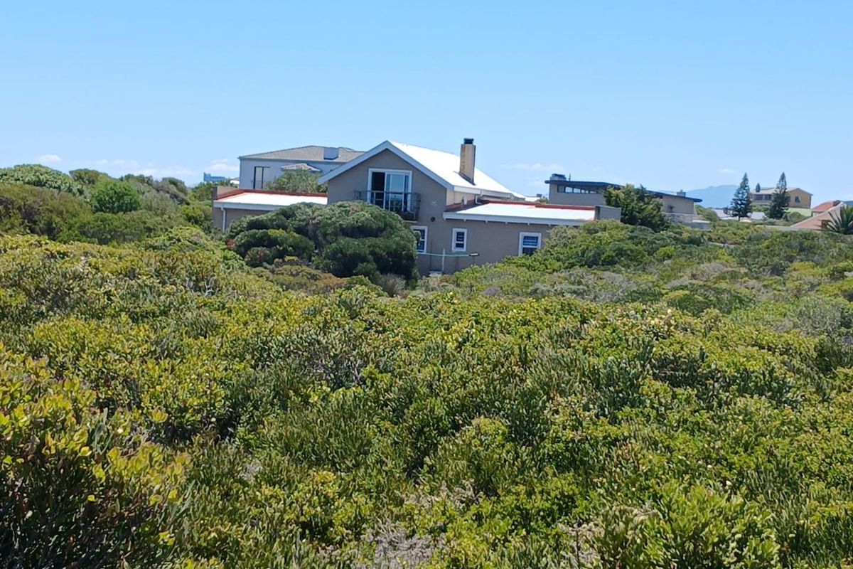 A view of a residential property nestled within dense coastal vegetation, showcasing the building's exterior structure and roofline.