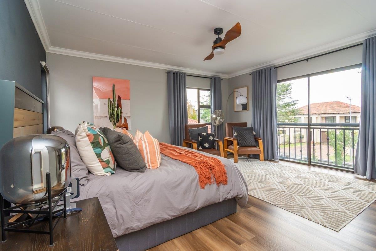 Spacious bedroom featuring wood-look flooring, a ceiling fan, and sliding glass doors opening onto a private balcony.