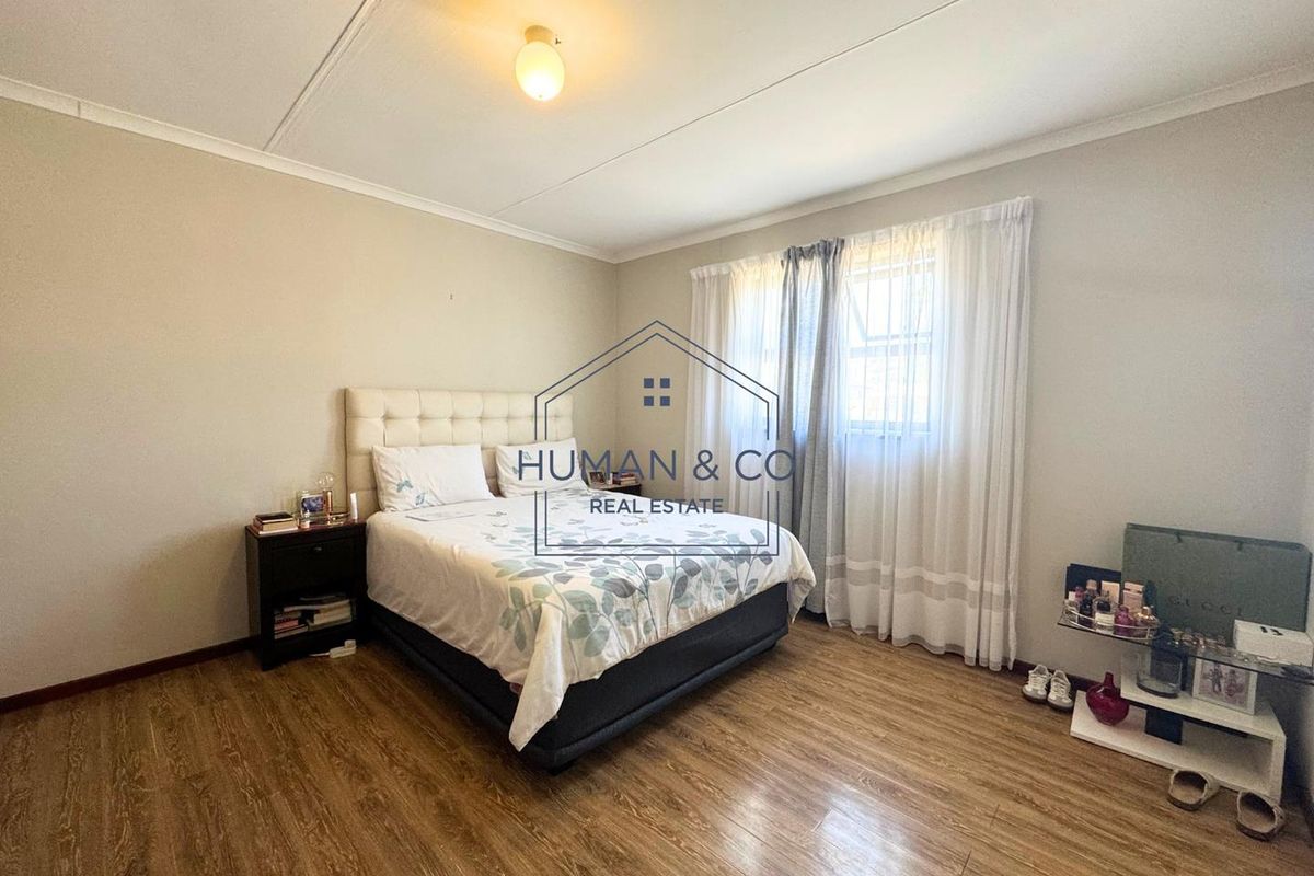 A well-lit bedroom featuring wood-look laminate flooring and neutral wall tones, providing a comfortable and functional living space.