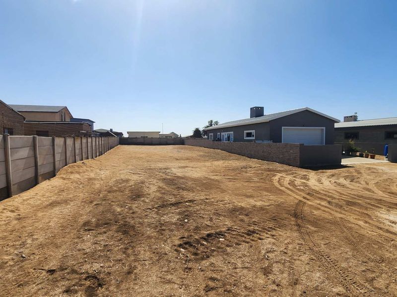 A large, vacant residential plot enclosed by precast concrete and brick boundary walls, offering a blank canvas for development.