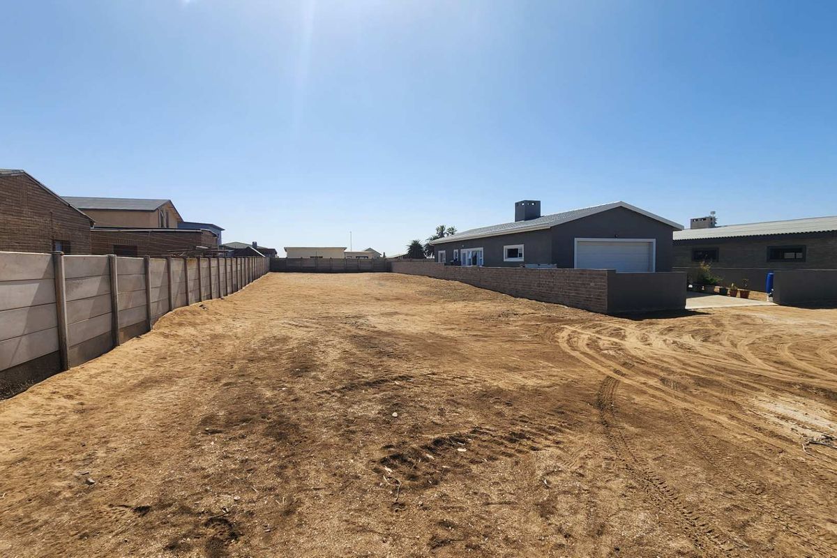 A large, vacant residential plot enclosed by precast concrete and brick boundary walls, offering a blank canvas for development.