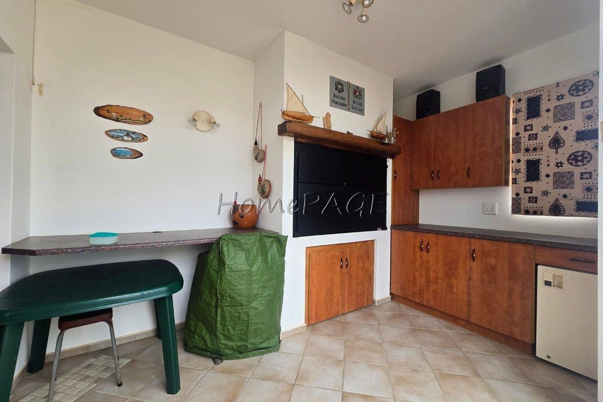 An indoor entertainment area featuring a built-in braai, wooden cabinetry, and tiled flooring.