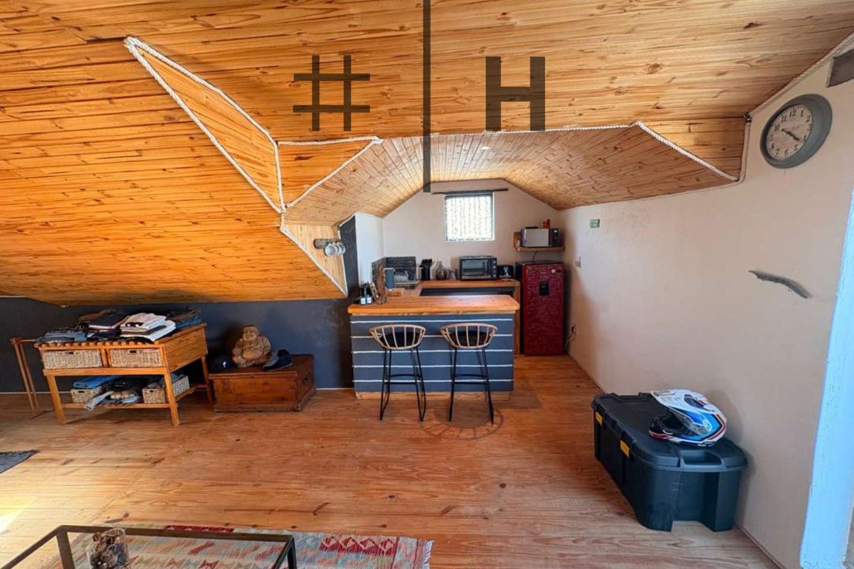 Attic-style kitchen area featuring a timber-clad vaulted ceiling, wooden flooring, and a built-in breakfast bar counter.