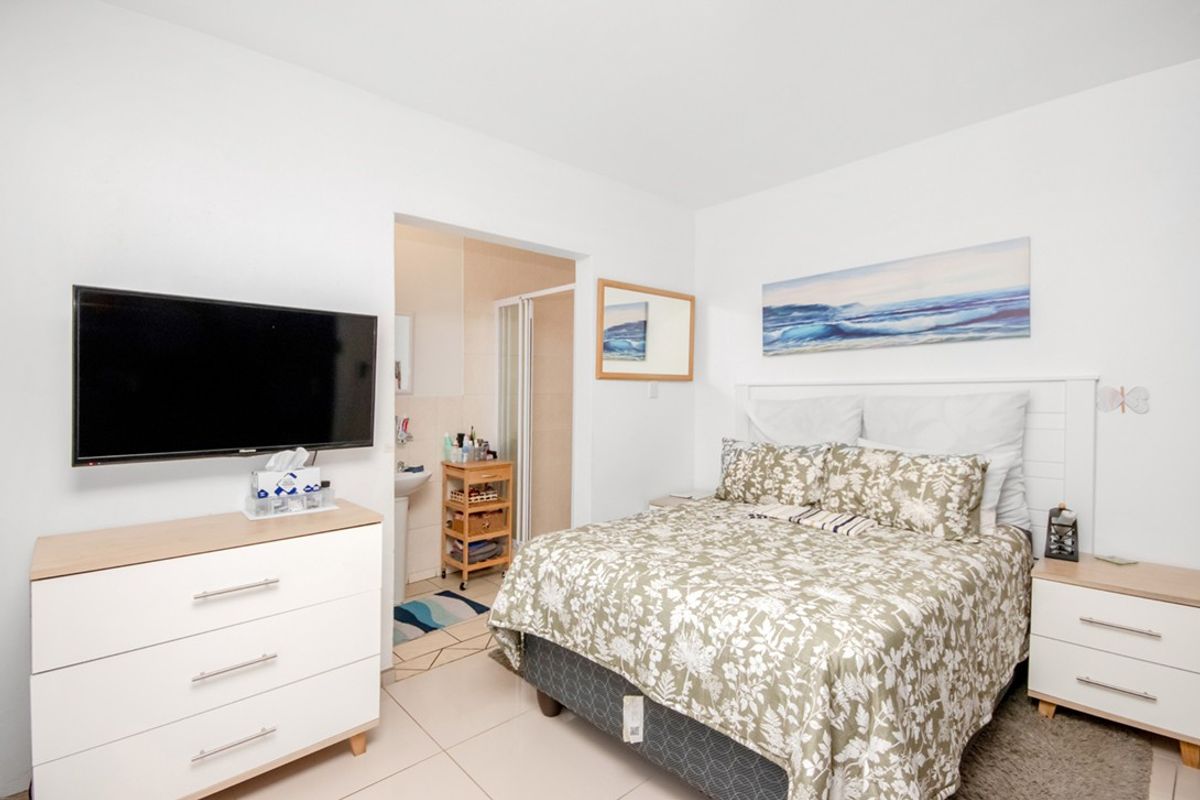 A well-maintained bedroom featuring tiled flooring and direct access to an en-suite bathroom.