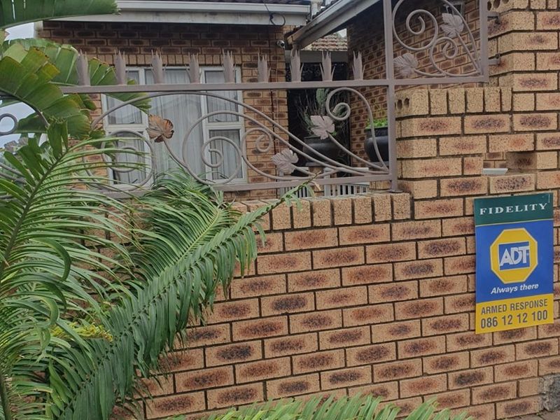 Front facade of the property featuring face brick construction and decorative wrought iron security fencing.