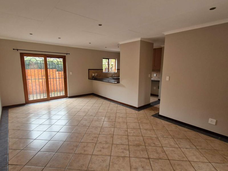 Spacious open-plan living area featuring tiled flooring, recessed lighting, and a sliding door leading to the exterior, with an adjoining kitchen space.