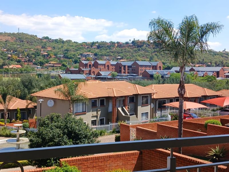 Elevated view overlooking a residential townhouse complex with terracotta tiled roofs, brick walls, and landscaped surroundings.