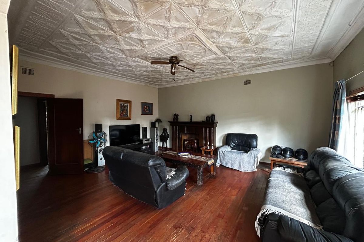 Spacious living room featuring original pressed metal ceiling, timber flooring, and a traditional fireplace mantle.