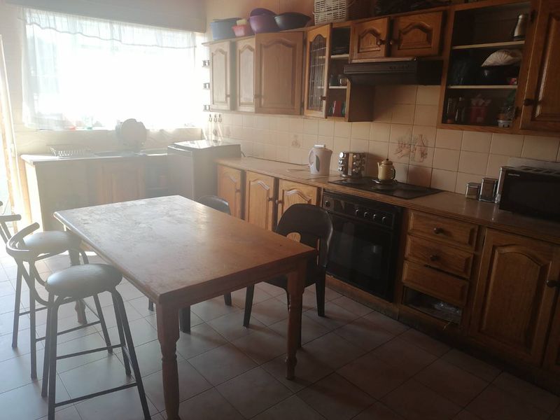 A dated kitchen featuring wooden cabinetry, built-in oven, electric hob, and tiled flooring, offering potential for a modern renovation.