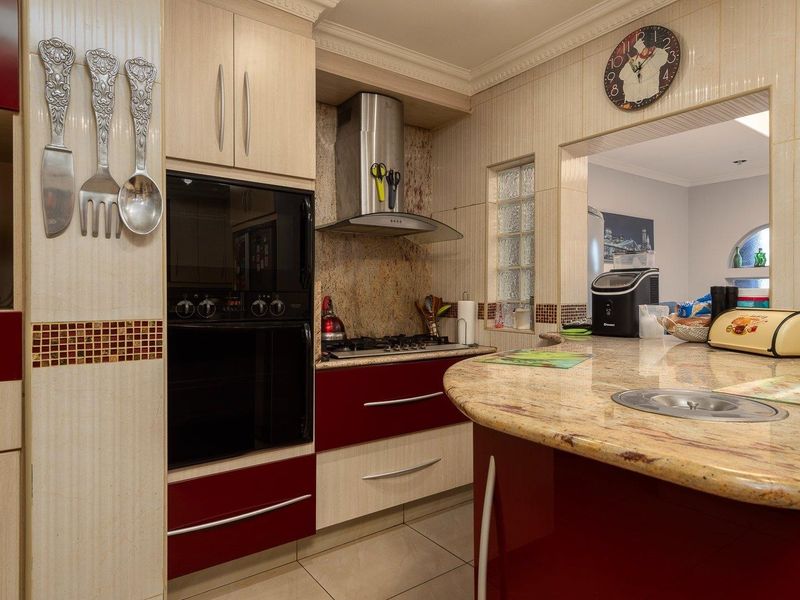 A functional kitchen featuring built-in oven, gas hob, extractor fan, and granite countertops with a breakfast bar, offering a practical layout for cooking.