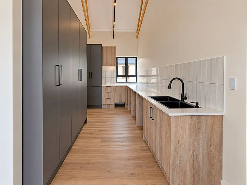 Modern kitchen featuring sleek dark grey and wood-grain cabinetry, stone countertops, a double sink with matte black fixtures, and exposed timber ceiling beams.