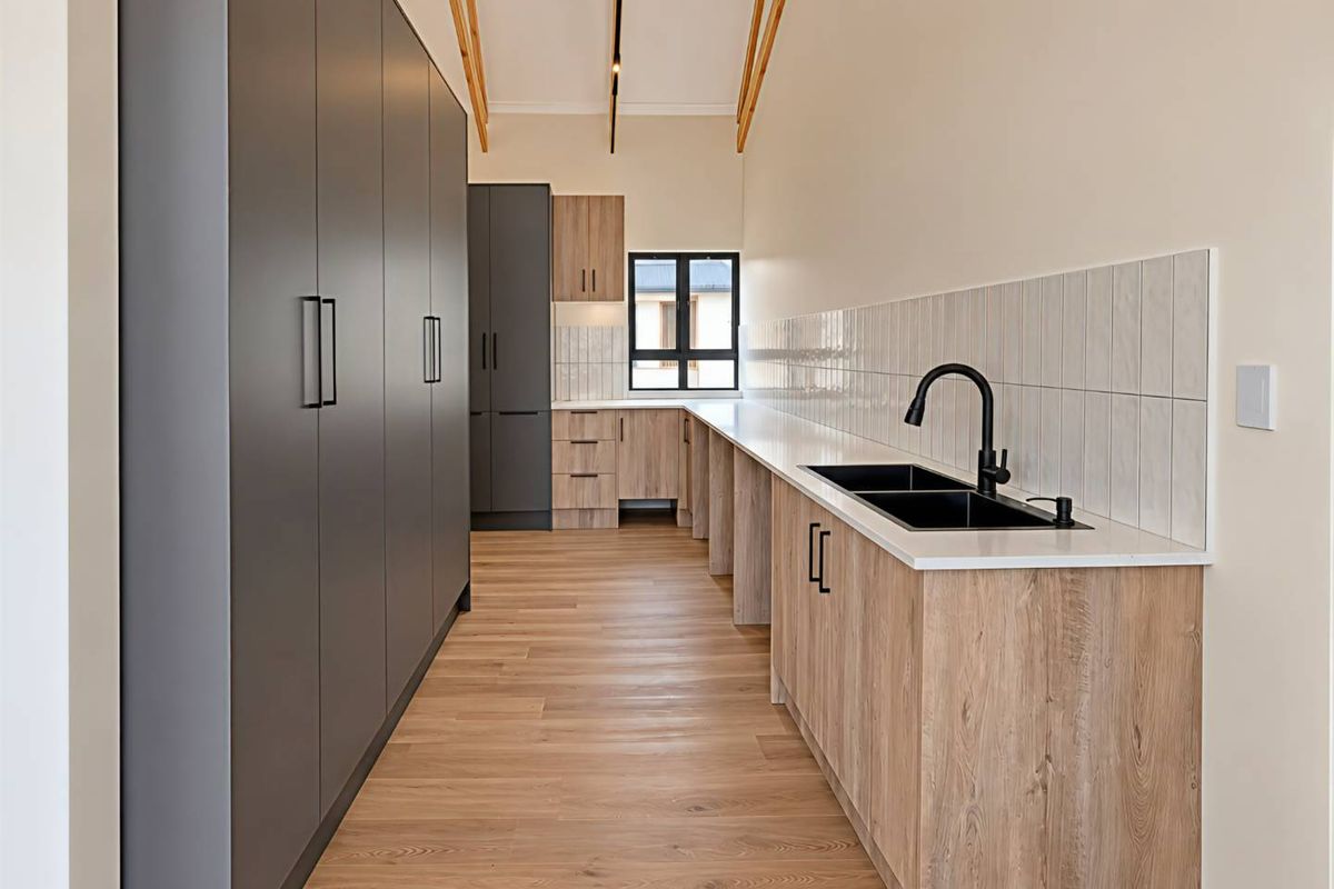 Modern kitchen featuring sleek dark grey and wood-grain cabinetry, stone countertops, a double sink with matte black fixtures, and exposed timber ceiling beams.