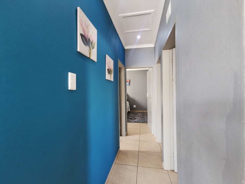 A clean and well-maintained hallway featuring tiled flooring and recessed ceiling lighting, providing access to multiple rooms within the home.