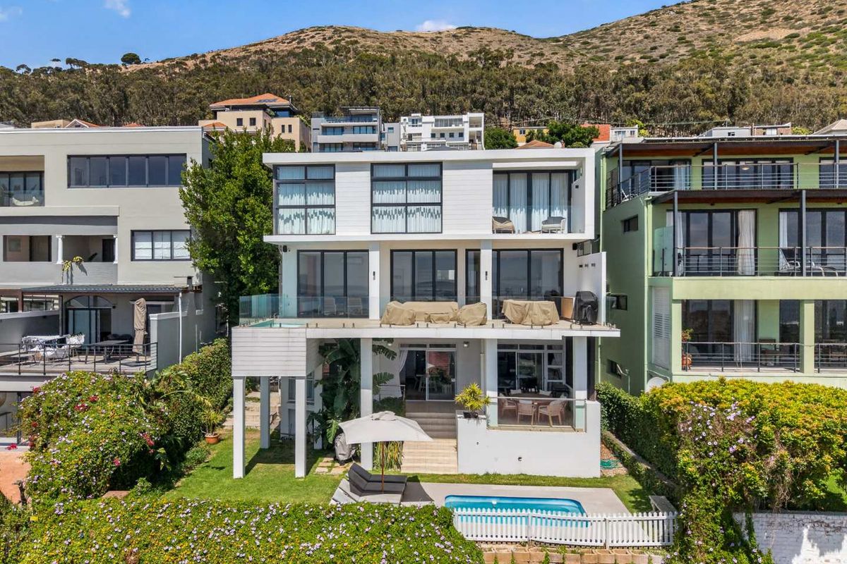 Rear view of a multi-story apartment building featuring tiered balconies, a private swimming pool, and a landscaped garden area.