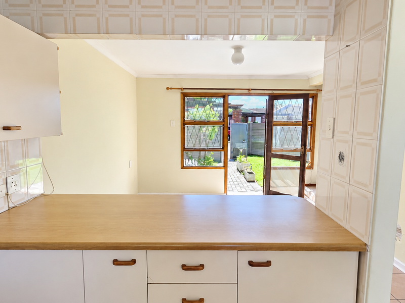 Open plan kitchen area featuring laminate countertops and built-in cabinetry, with direct access to the rear garden through a timber-framed door.