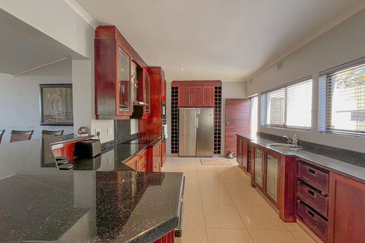 Spacious kitchen featuring dark granite countertops, rich wood cabinetry, integrated wine storage, and tiled flooring with ample natural light.