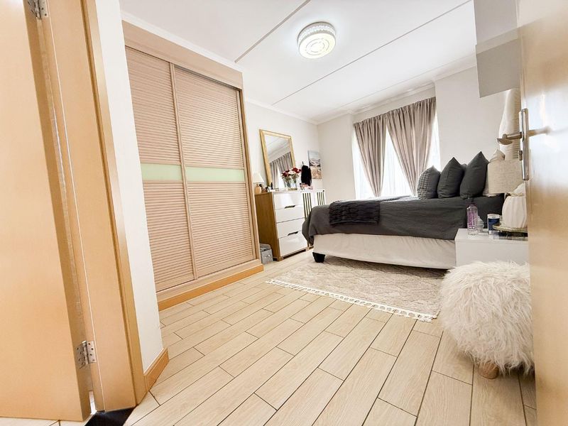A well-maintained bedroom featuring light-toned tiled flooring, a built-in sliding door wardrobe, and neutral wall finishes.