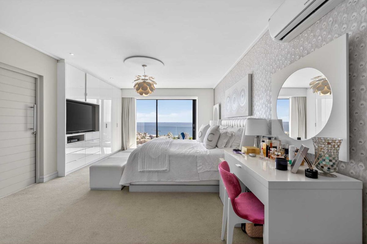 Spacious master bedroom featuring built-in high-gloss cabinetry, split-system air conditioning, and large sliding glass doors offering expansive ocean views.