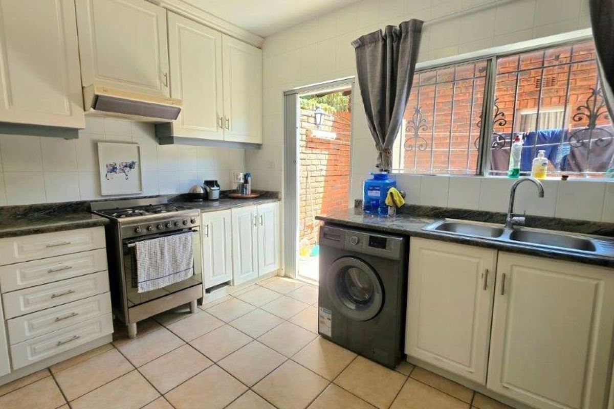 Functional kitchen featuring white cabinetry, stone countertops, a gas stove, and direct access to an outdoor area through a side door.