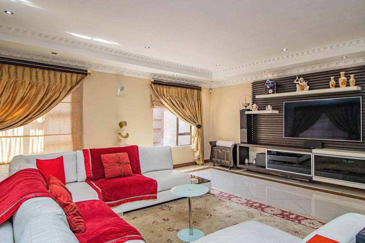Spacious living room featuring polished tile flooring, decorative crown molding, recessed lighting, and a custom built-in media wall unit.