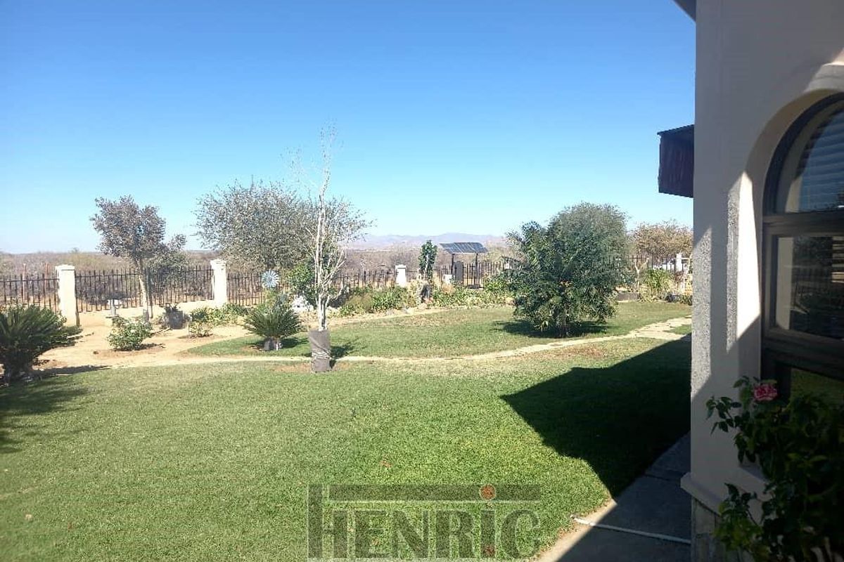 A well-maintained rear garden featuring a manicured lawn, established landscaping, and perimeter fencing, offering a pleasant outdoor space with clear views.