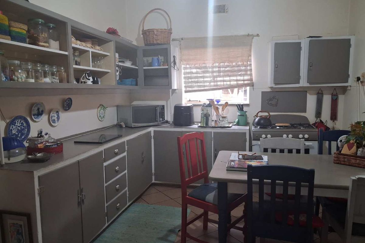 A functional kitchen featuring built-in cabinetry, a gas stove, and a dedicated dining area with tiled flooring and natural light.