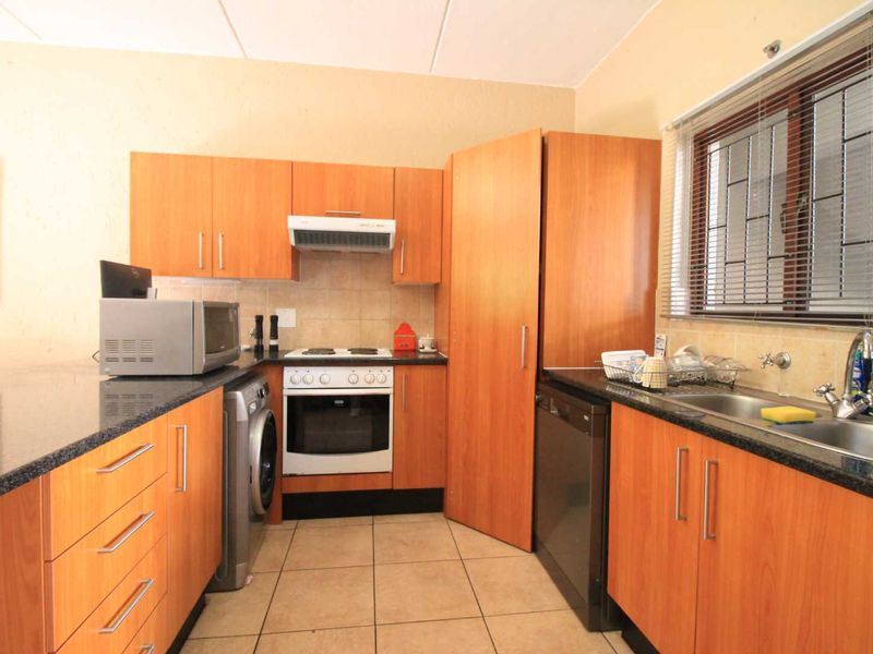 Functional kitchen featuring laminate cabinetry, granite countertops, built-in oven with hob, and tiled flooring, offering a practical layout for daily meal preparation.