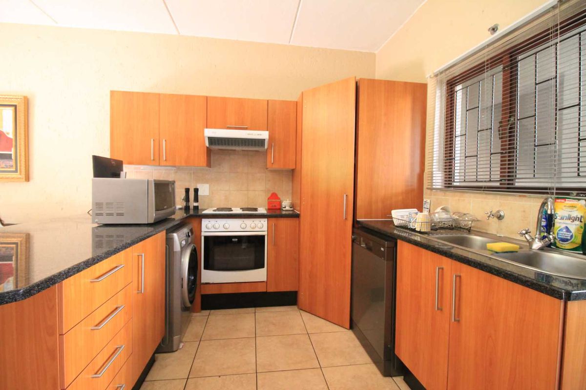 Functional kitchen featuring laminate cabinetry, granite countertops, built-in oven with hob, and tiled flooring, offering a practical layout for daily meal preparation.