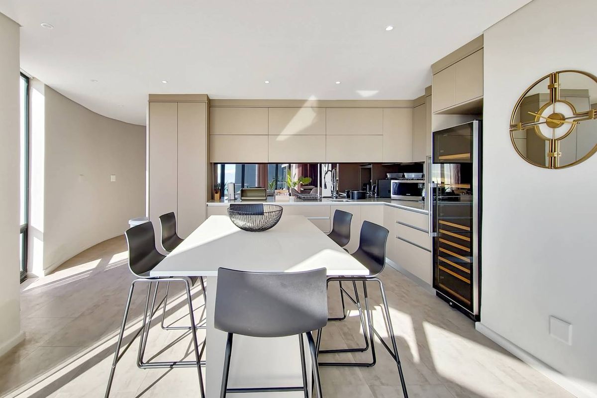 Modern open-plan kitchen featuring sleek cabinetry, integrated appliances, a built-in wine cooler, and a central island with breakfast bar seating.