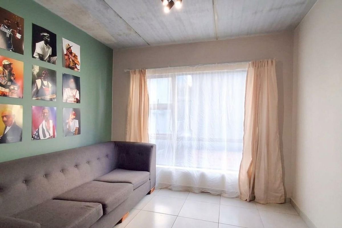 A living room featuring tiled flooring, a large window with curtains, and a painted accent wall.