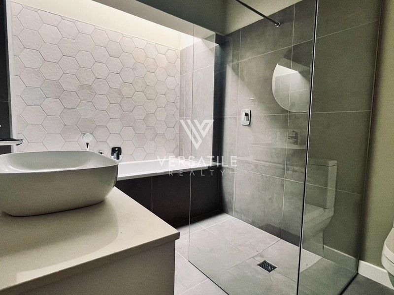 Modern bathroom featuring a walk-in shower with glass screen, a freestanding bathtub, vessel sink on a vanity, and contemporary hexagonal wall tiling.