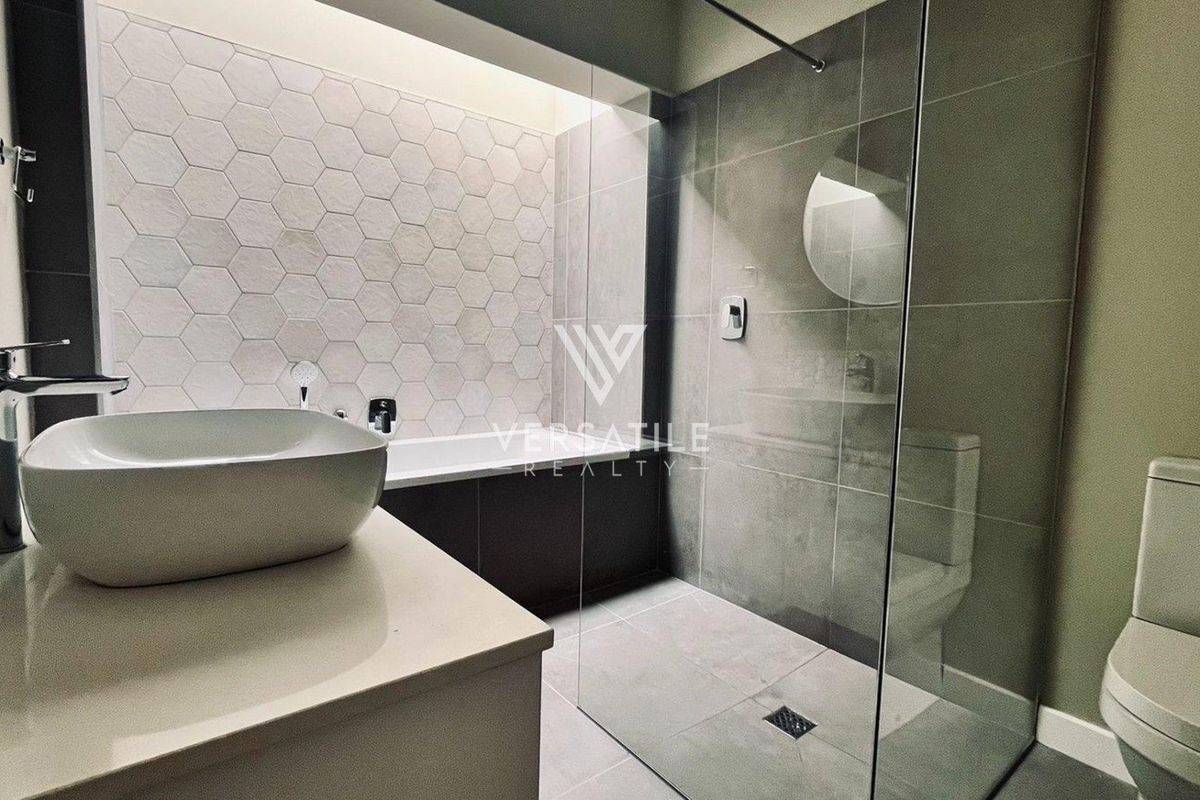 Modern bathroom featuring a walk-in shower with glass screen, a freestanding bathtub, vessel sink on a vanity, and contemporary hexagonal wall tiling.