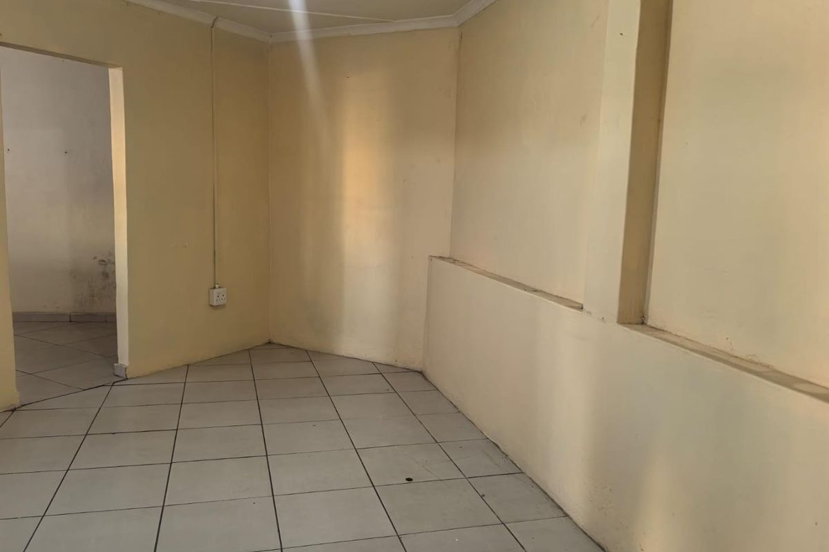 An empty, neutrally-toned living area featuring tiled flooring and coved ceilings, presenting a blank canvas ready for renovation and modernization.