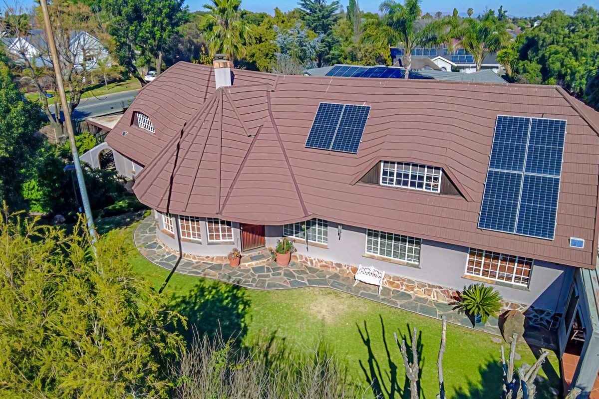 Aerial view of a residential property featuring a tiled roof, solar panels, and a landscaped garden with a stone pathway.