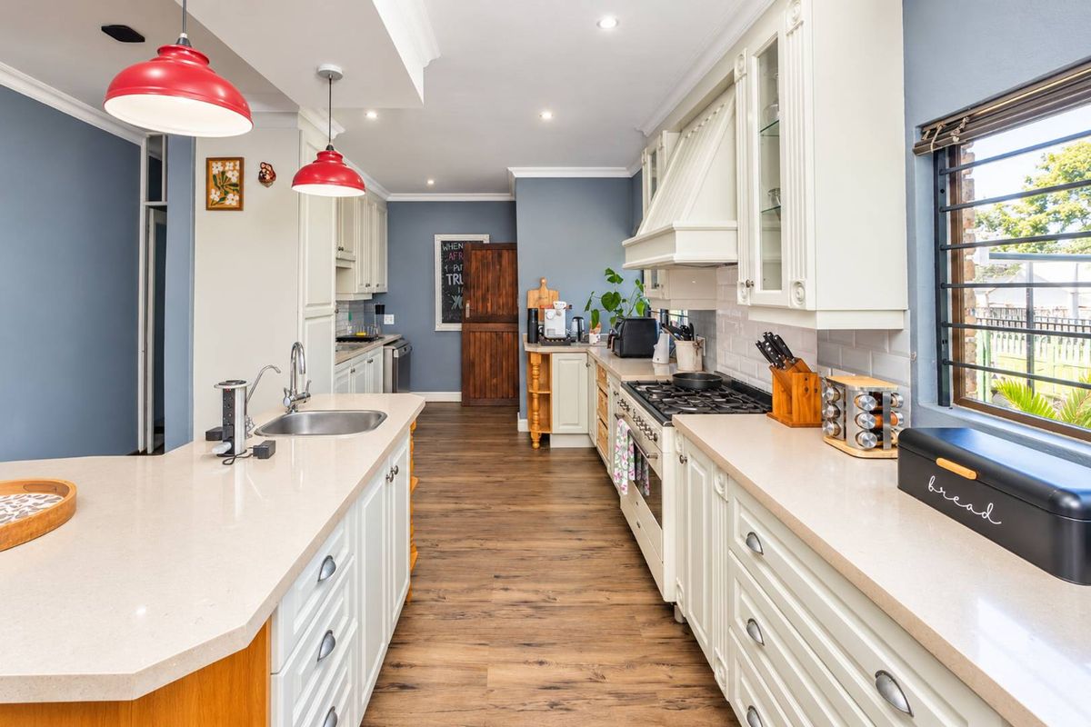 A well-appointed kitchen featuring shaker-style cabinetry, stone countertops, a central island, and integrated gas cooking appliances with a classic subway tile backsplash.
