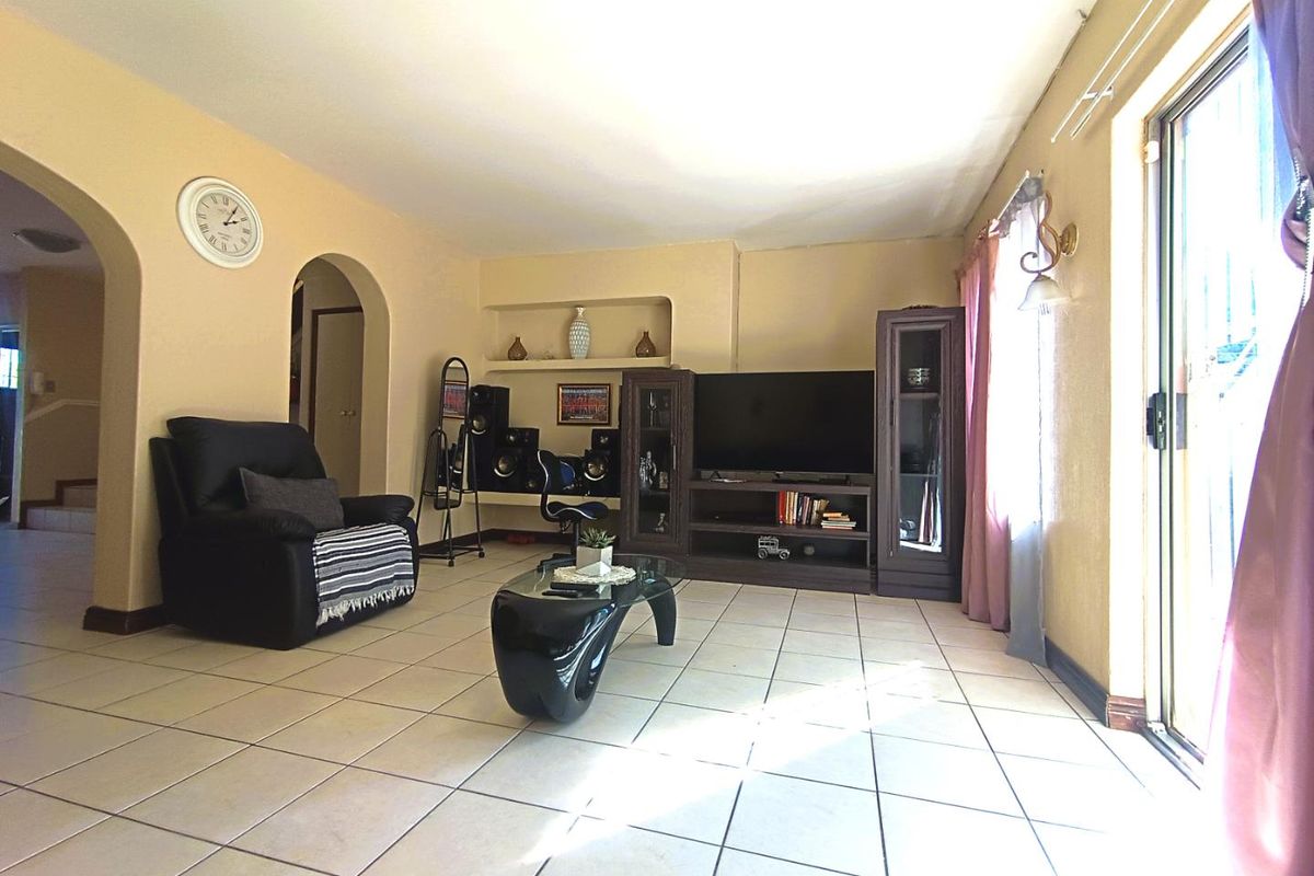 Spacious living room featuring tiled flooring, arched doorways, and a built-in wall niche, with sliding glass doors providing access to the exterior.