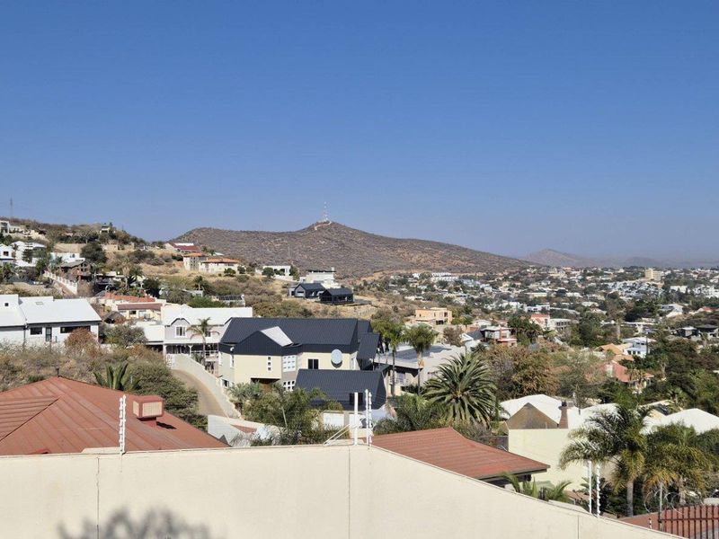 An elevated panoramic view overlooking a residential neighborhood with rolling hills and distant mountain scenery.
