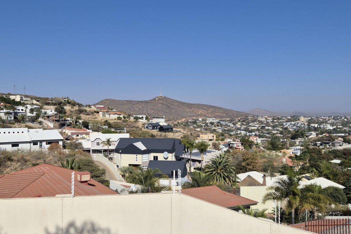 An elevated panoramic view overlooking a residential neighborhood with rolling hills and distant mountain scenery.
